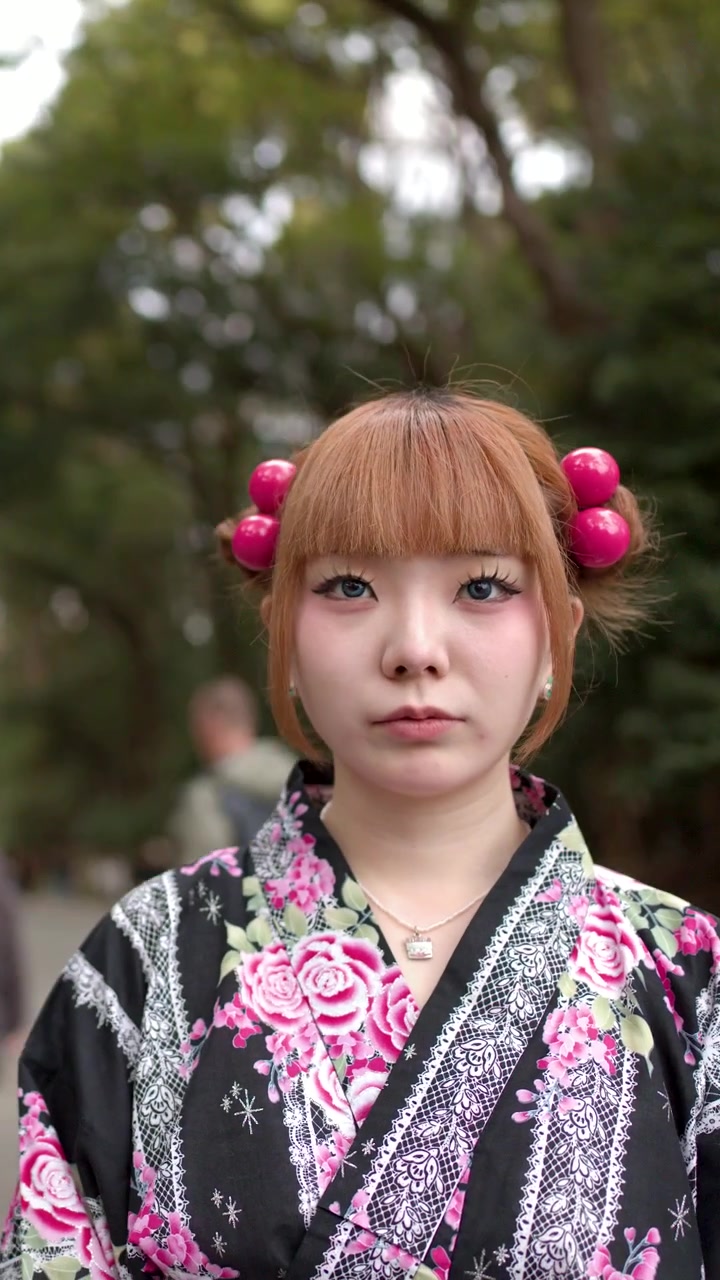 Japonská žena v tradičním květinovém kimonu stojí venku poblíž brány šintoistické svatyně