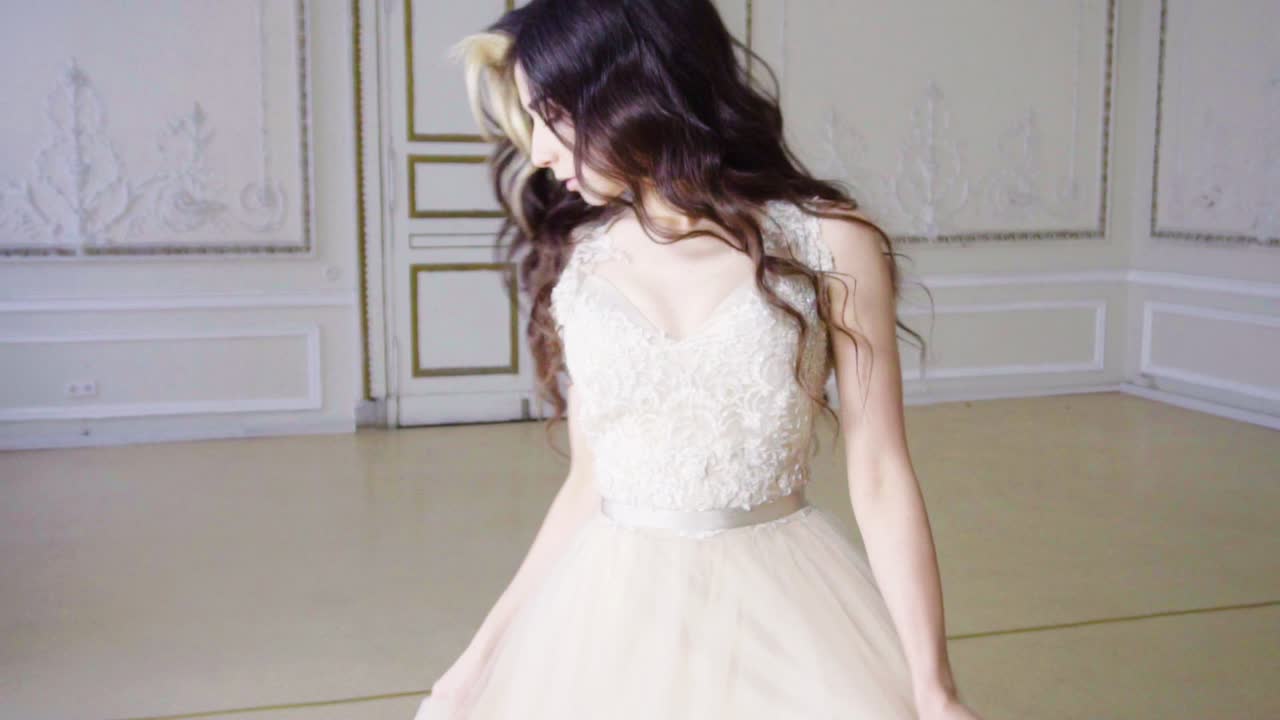 молодая девушка с длинными волосами танцует в длинном вечернем платье