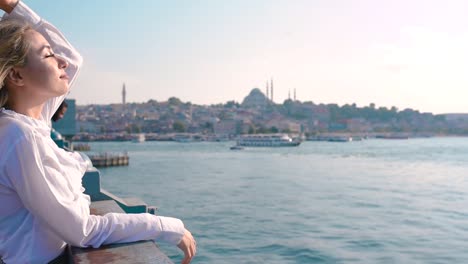 slow motion:beautiful girl stands over galata bridge and enjoys view of bosphorus in istanbul,turkey