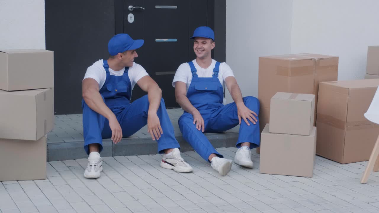 dos trabajadores de la compañía de mudanzas tienen un descanso mientras están sentados en el escalón