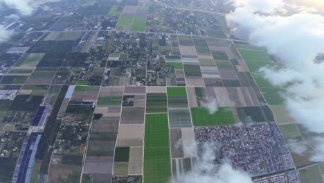fpv drone flies above the landscape divided into the urban areas and farm fields. view of the city from top.