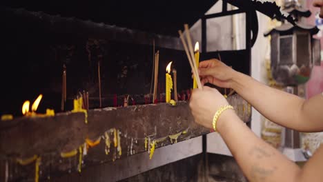 person lighting incense and candles at a temple