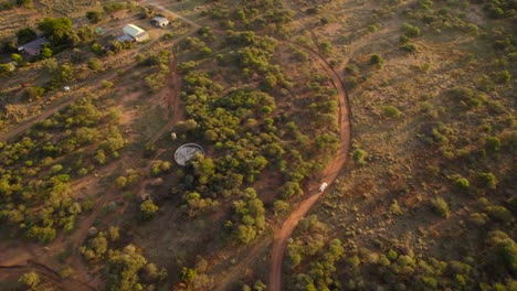 Birds-eye-view-of-car-driving-on-unpaved-roads-of-mixed-woodland-and-grassland-of-savannah