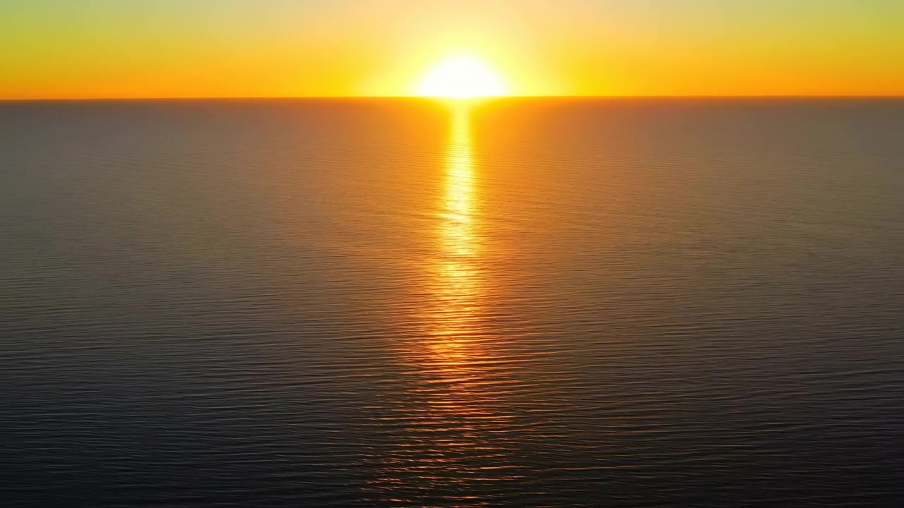 Wide horizontal view of a tranquil seascape at sunset with the sun centered on the horizon, warm orange and yellow gradient sky, and golden light reflecting
