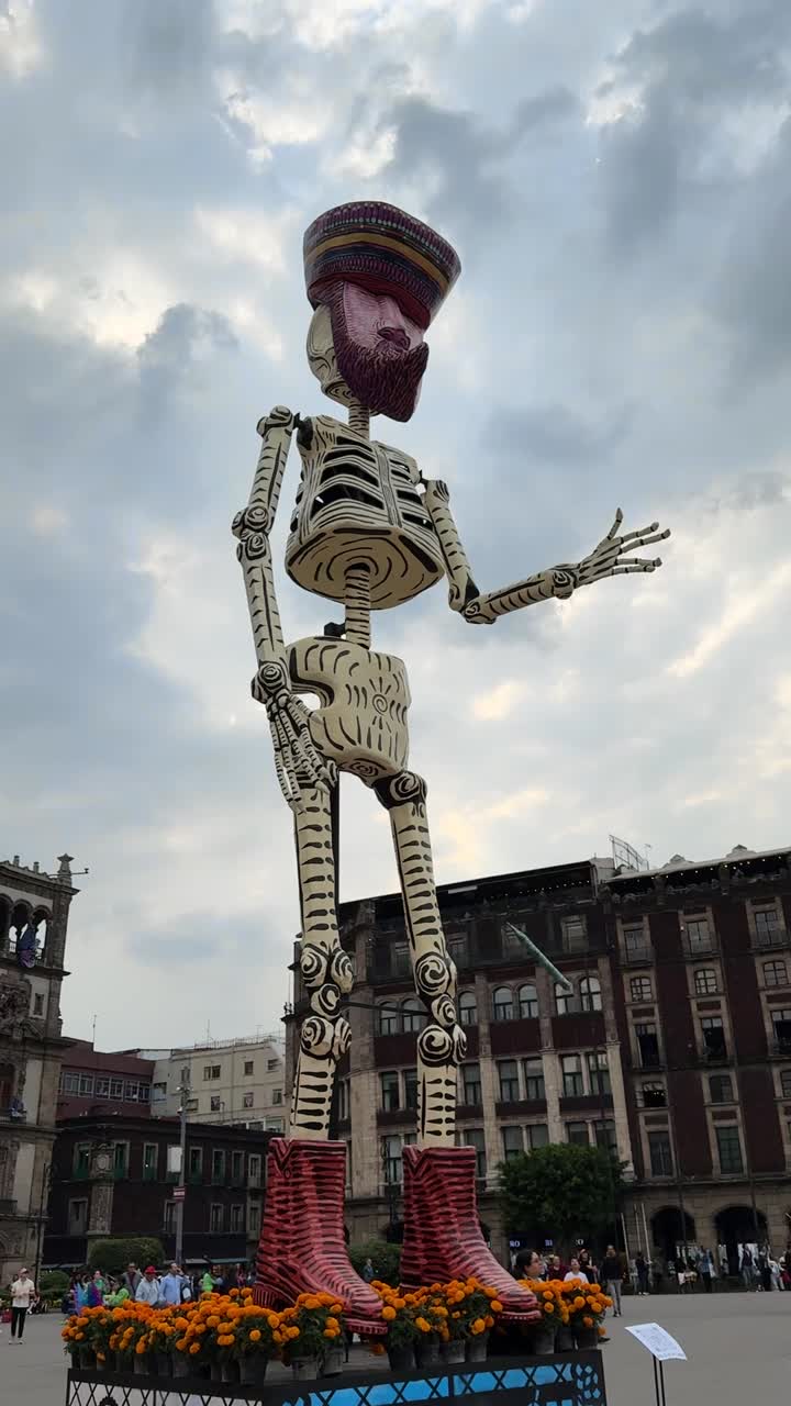 Massive Mexican skeleton sculpture with raised arm under cloudy sky for Day of the Dead festival