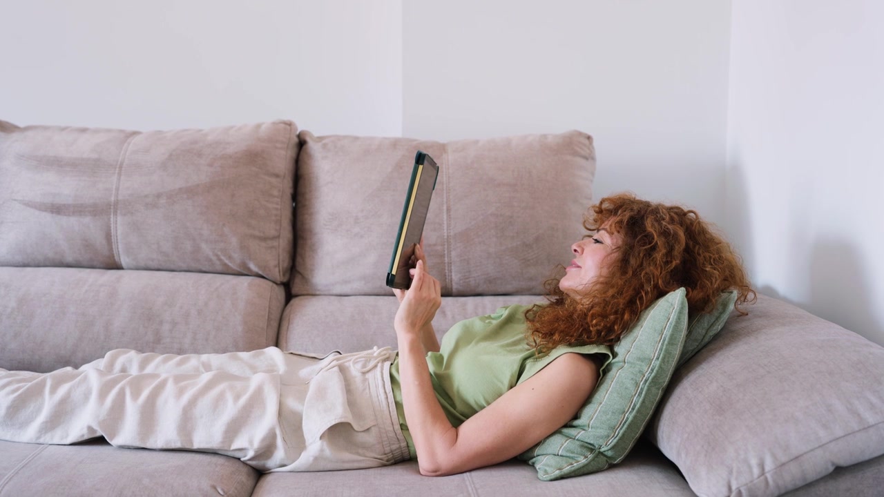 Donna che si rilassa sul divano e usa un tablet a casa