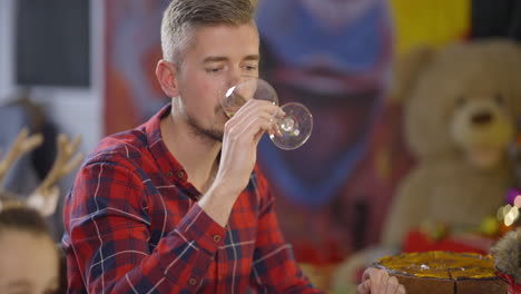 a man drinking wine at a table during a christmas celebration
