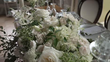 elegant white floral centerpiece on a dining table set for an event with fine china