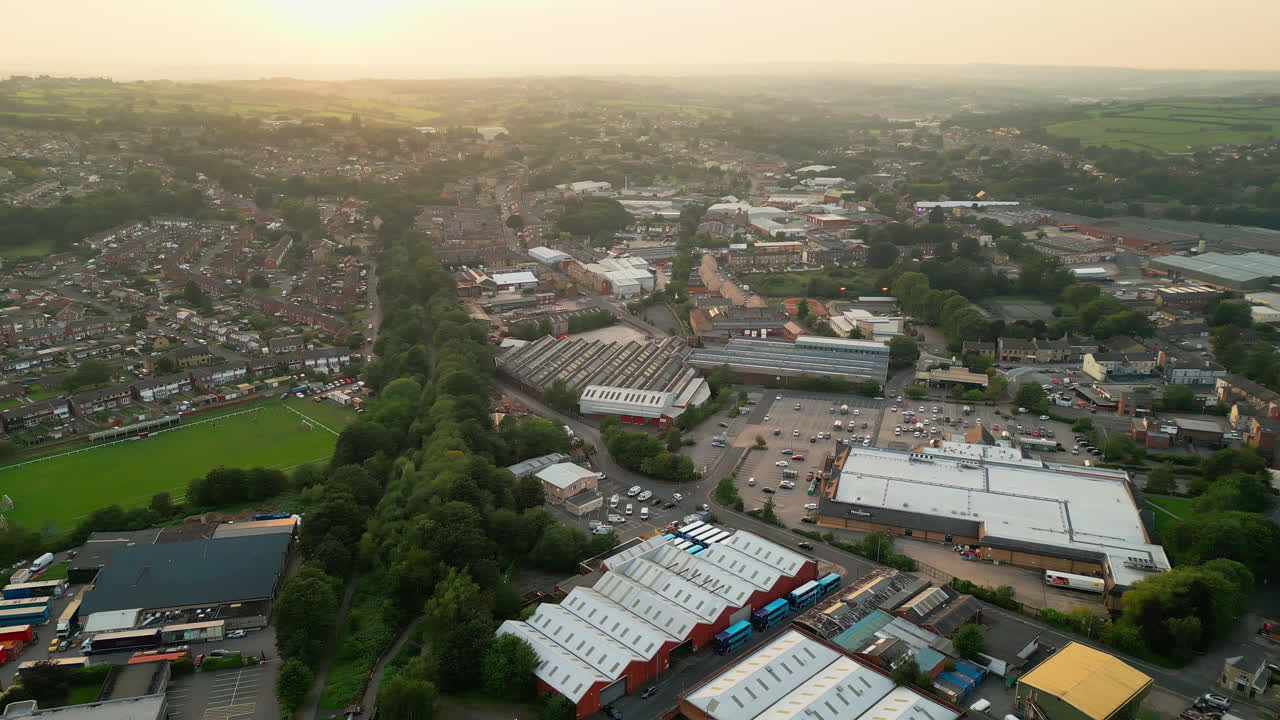 un video capturado por un avión no tripulado de heckmondwike, reino unido, revela estructuras industriales, calles bulliciosas y un antiguo centro de la ciudad contra el telón de fondo de yorkshire en una noche de verano.