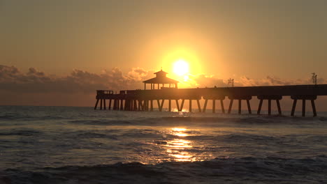 Close-up-sunrise-sunset-at-pier-by-the-ocean-and-beach