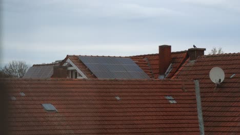paneles solares modernos en el techo rojo de la casa vieja durante el día nublado