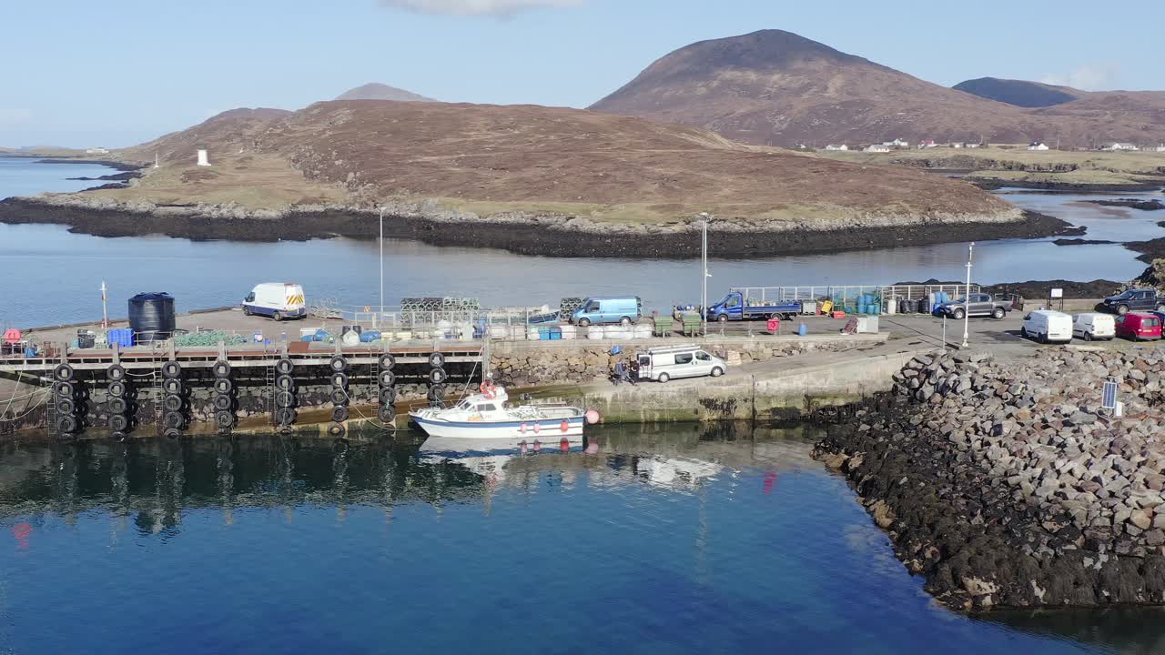 Drohnenaufnahme der Hügel der Isle of Harris hinter dem Pier und Hafen von Leverburgh