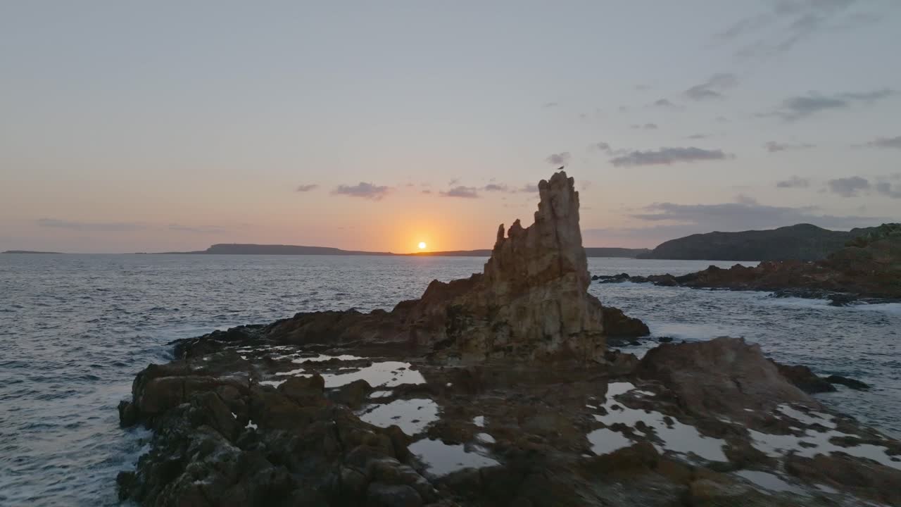 Sorvolo al tramonto di una solitaria formazione rocciosa vicino alla spiaggia di Cala Pregonda