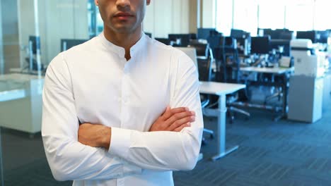 male executive standing with arms crossed in office