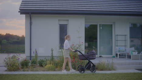 woman walking with baby stroller near modern house