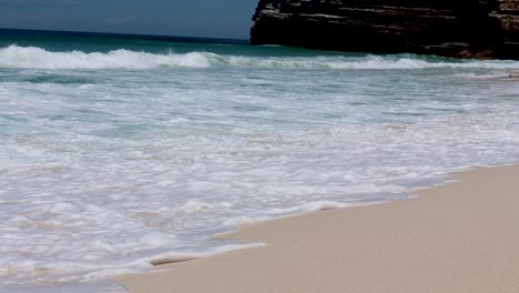 Blue-waves-breaking-on-a-golden-beach,-low-shot-at-normal-speed-4K-at-30fps