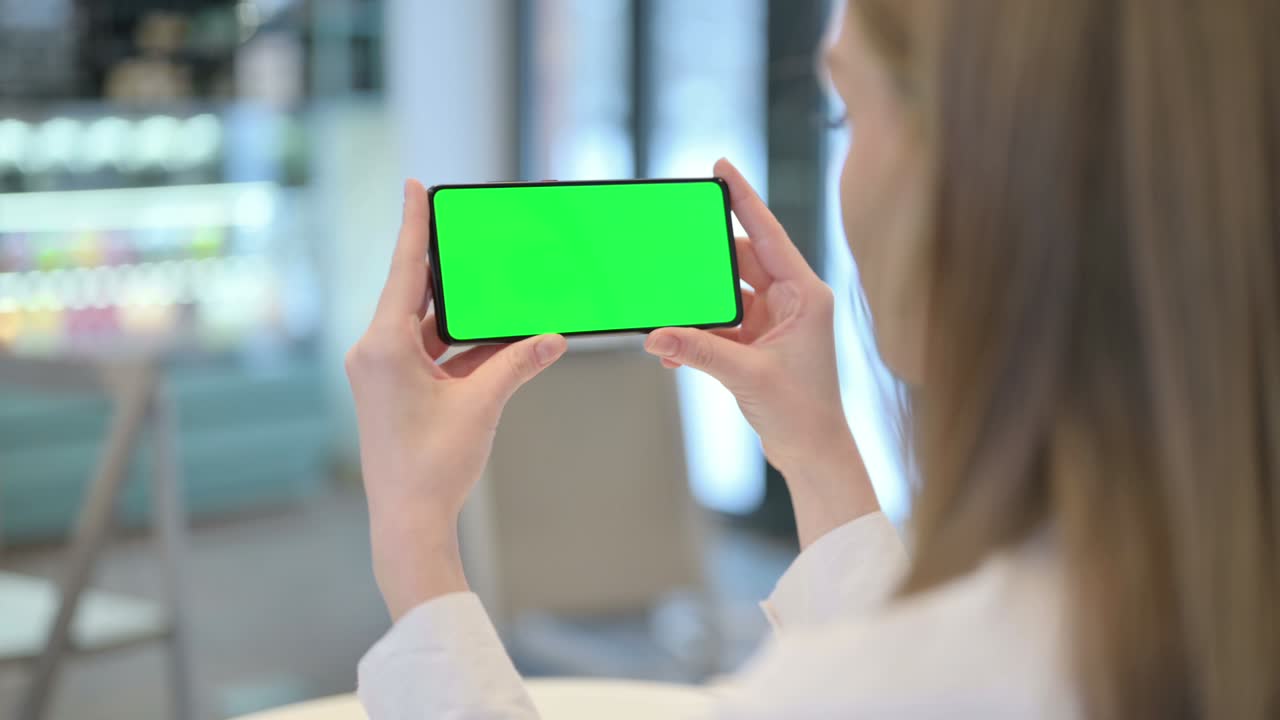 초록색 크로마 키 스크린으로 스마트폰을 보는 여자