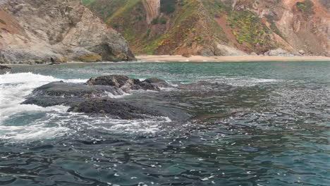 Low-altitude-aerial-of-coastal-terrain-in-Big-Sur,-dynamic-ocean