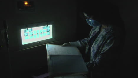 a dental hygienist looks at xrays in a darkened room 1