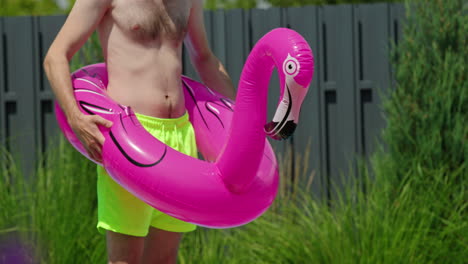 hombre con flamenco flotando en la piscina