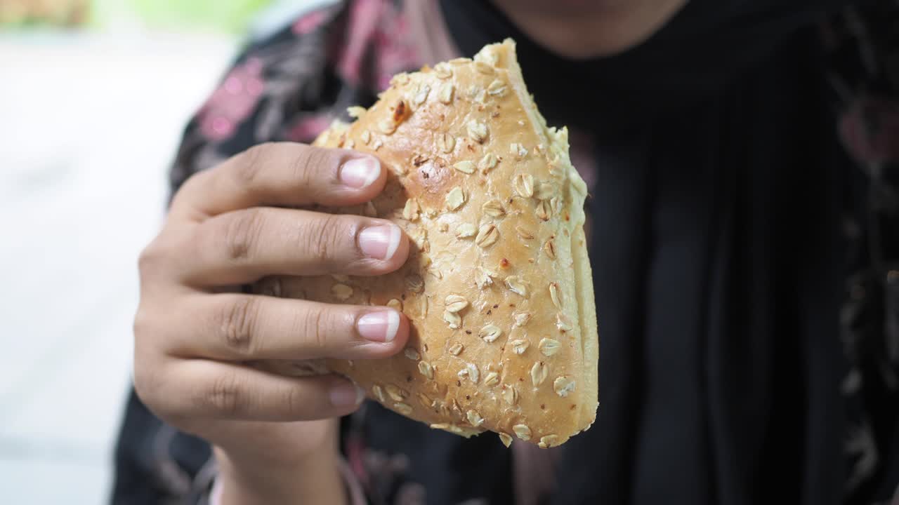 Person eating an oatmeal bread sandwich