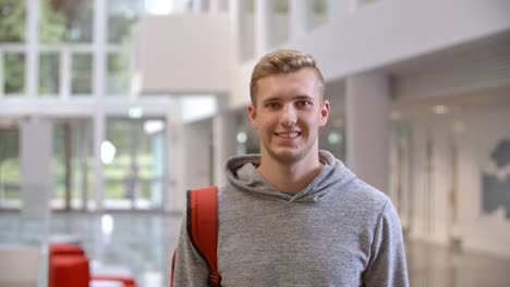 White-male-university-student-walking-into-focus-in-a-lobby