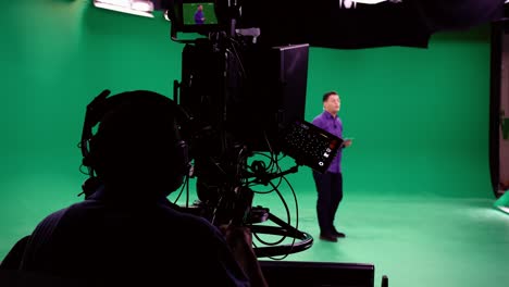 the cameraman follows the announcer in a professional green screen studio. the professional looks all the shooting equipment; lights, camera, green screen