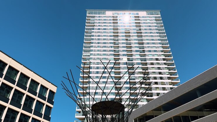 Grattacieli incorniciano un'installazione artistica. L'architettura moderna incontra un'opera d'arte sorprendente in un contesto urbano sotto un cielo azzurro brillante