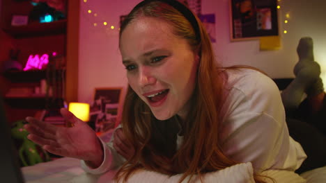 young woman smiling at laptop in bed