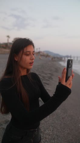 woman taking a selfie on the beach at sunset