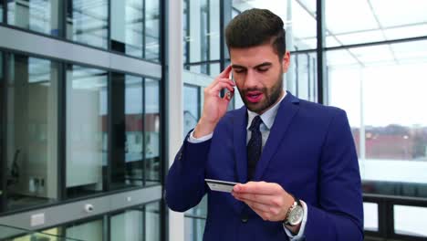businesswoman using credit card while talking on mobile phone