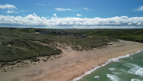 Holywell-Bay-In-Cornwall-Mit-Sandstrand-Und-Meereswellen-Aus-Einer-Luftdrohne,-Die-über-Das-Wasser-Schwenkt