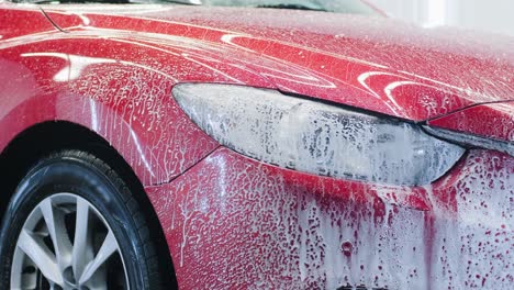 man worker washing red car on a car wash.