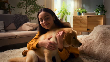 young woman embracing her golden retriever puppy at home