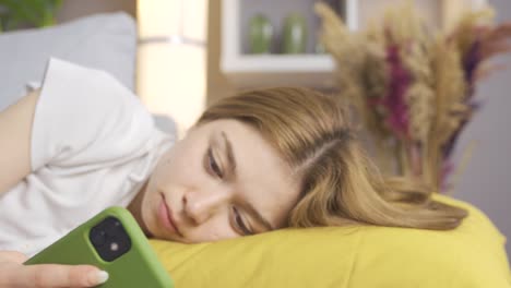 mujer joven adicta al teléfono acostada en el sofá en casa.