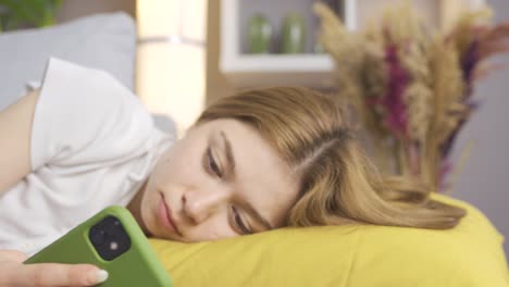 phone addicted young woman lying on sofa at home.