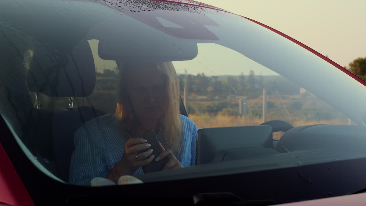 Female car driver with phone in the countryside