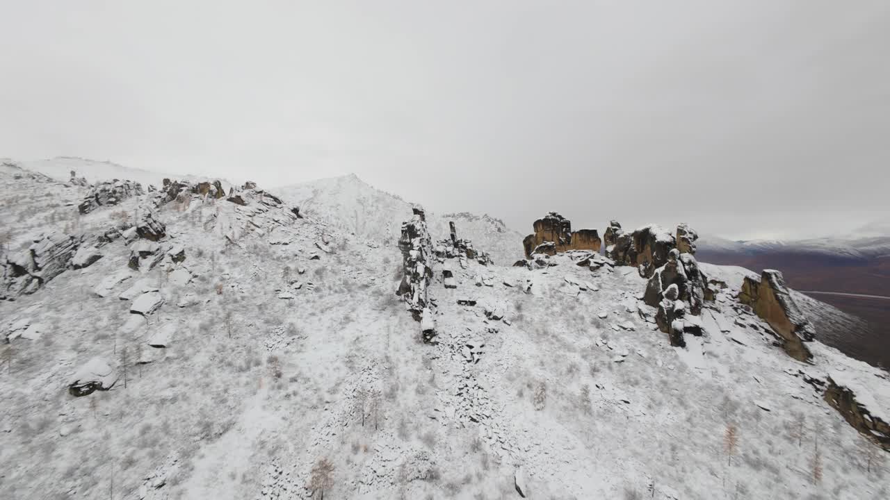 Experience the breathtaking beauty of snow-draped mountains from above as a drone captures the intricate patterns of the landscape against a soft, dusky sky.