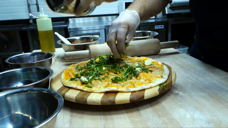 putting arugula on pizza cooking