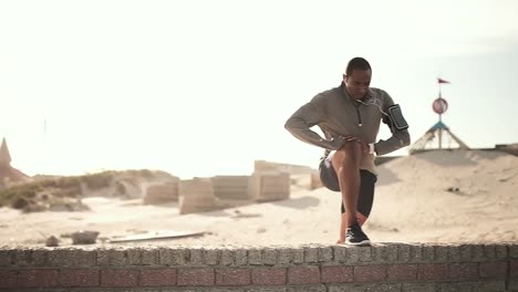 man stretching his leg on the beach