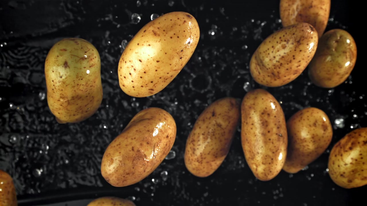Movimento super rallentato di acqua che schizza su patate crude