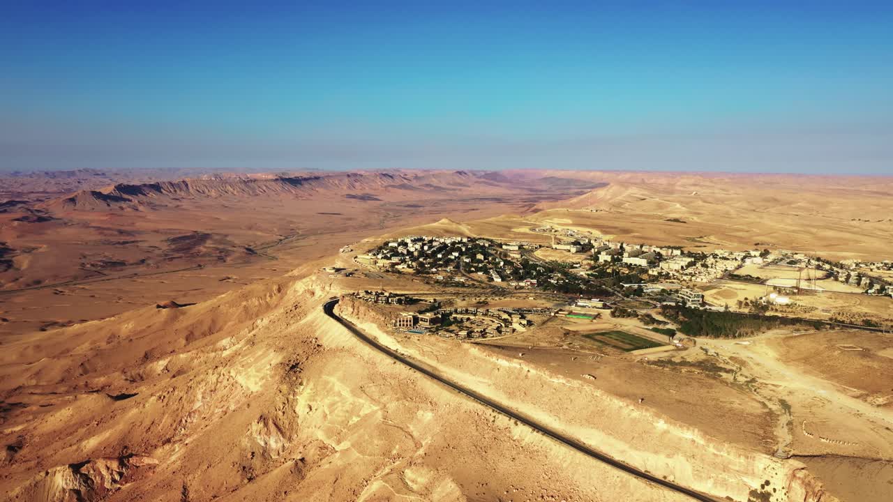 Vakker landsby i Makhtesh Ramon med fantastisk utsikt over det mørkefargede Mitzpe Ramon i Israel på en solrik dag.