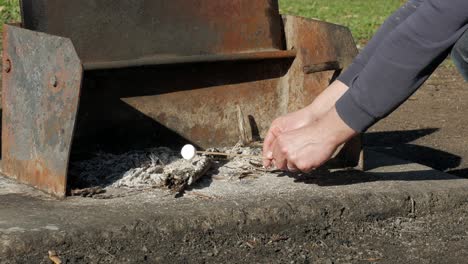 man cooking marshmallow over hot ash on a twig