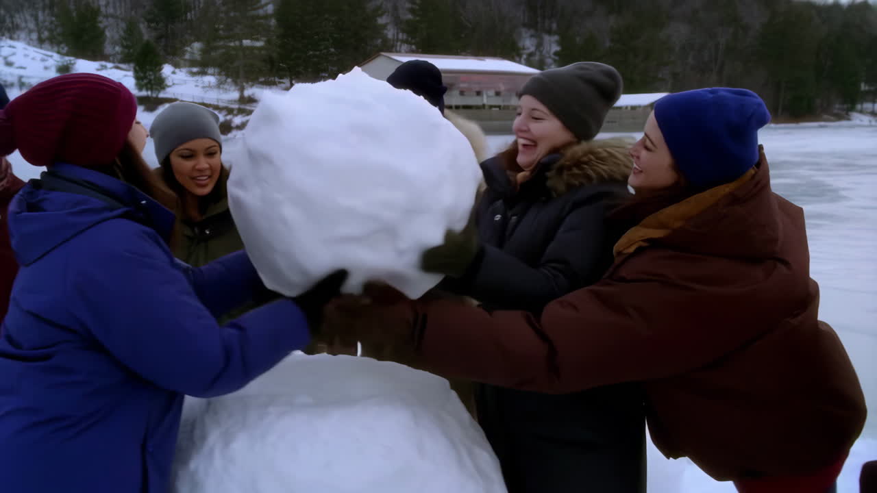 Women Laughing While Building a Snowman on an Icy Lake