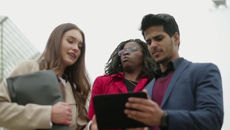 three young people outside googling on tablet place to go