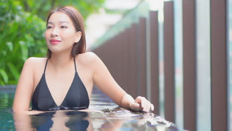 인피니티 풀 가장자리에 기대어 있는 젊은 매력적인 여성의 클로즈업