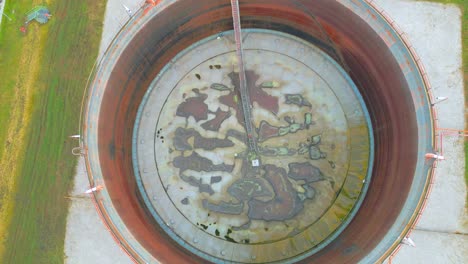 vista superior del tanque de almacenamiento de petróleo con techo oxidado flotando en la superficie del líquido almacenado