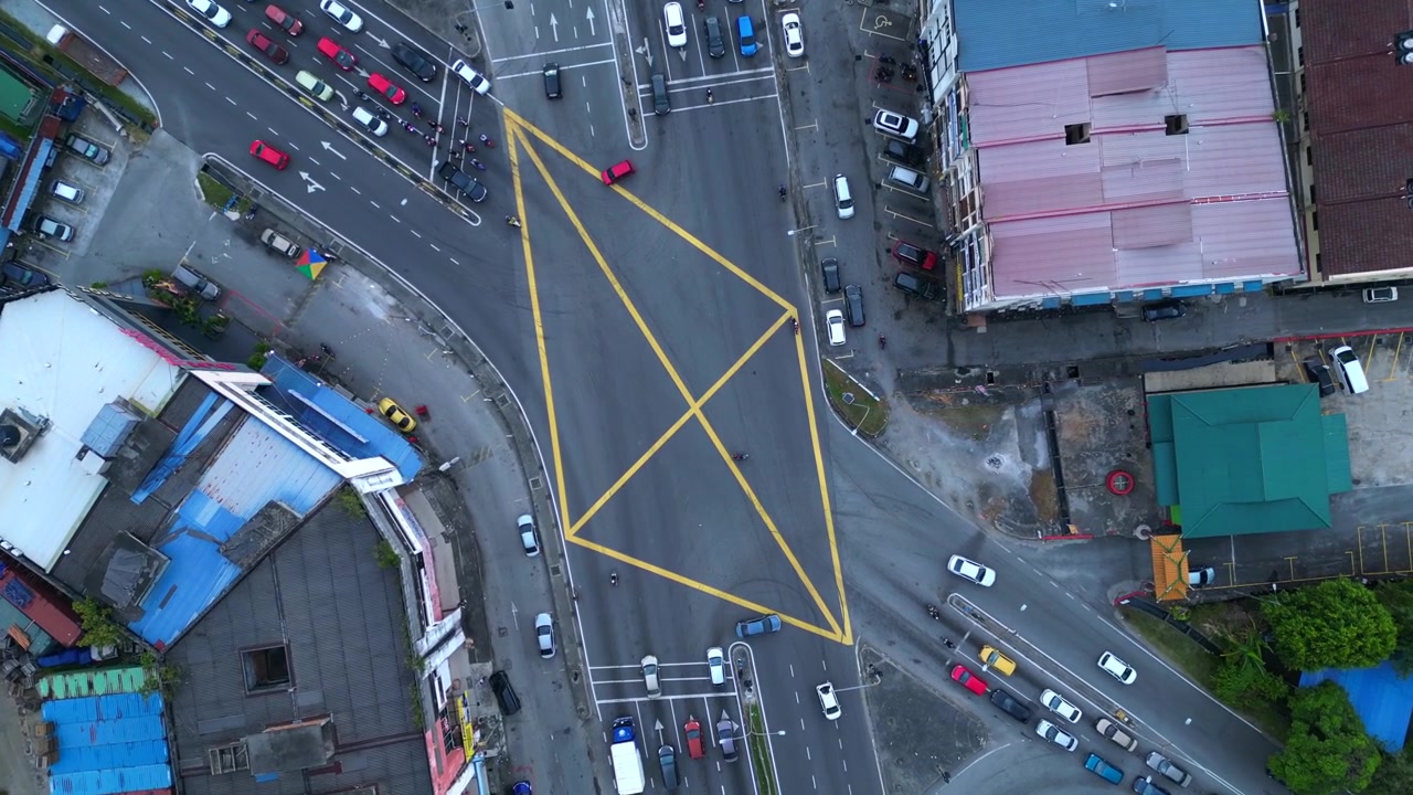 vertical bird's eye view, cars and motorbikes driving through a yellow marked box junction in Port Klang, Malaysia. Magic aerial view drone camera pointing down