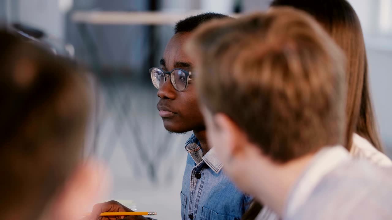 Multiethnic young professionals, business partners at team meeting, focused African American male worker speaking.