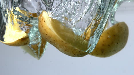 potato slices falling in water on white background